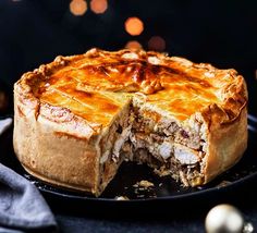 a meat pie is cut in half on a black plate with a blue napkin and silver ornaments