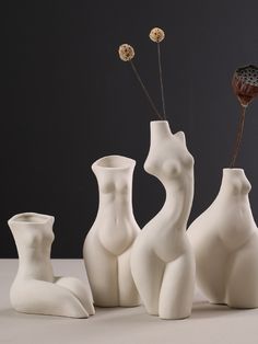 three white vases with flowers in them sitting on a table next to each other