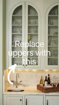 a kitchen with white cabinets and wine glasses on the counter top, along with two bottles of wine