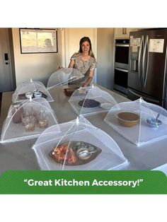 a woman standing in front of a kitchen counter covered with clear plastic containers and plates