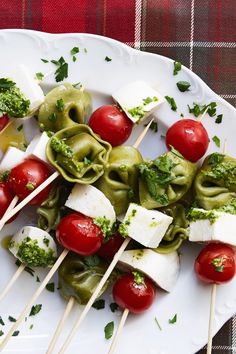 a white plate topped with pasta and veggies on skewers next to ketchup