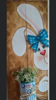 a potted plant sitting on top of a wooden shelf next to a bunny sign