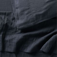 an unmade bed with dark blue sheets