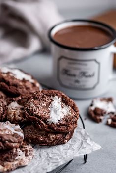 chocolate cookies with powdered sugar are on a plate next to a cup of coffee