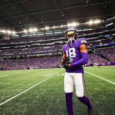 a football player is standing on the field with his hands in his pockets and holding a ball