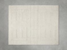 a white rug with square and rectangle designs on it, against a gray wall