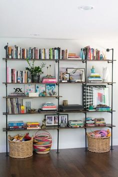 the bookshelf is filled with many books and baskets on it's sides