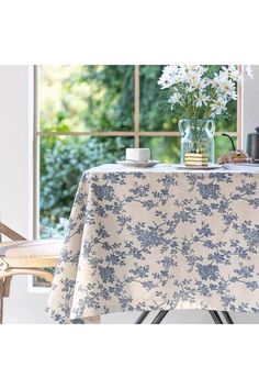 a table covered with a blue and white flowered tablecloth next to a window