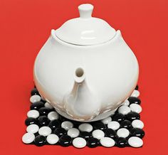 a white tea pot sitting on top of black and white balls