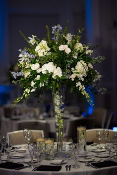 a vase filled with white flowers sitting on top of a table covered in silverware