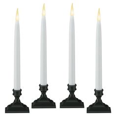 three white candles are lined up in a row on black bases with one candle lit and the other turned off