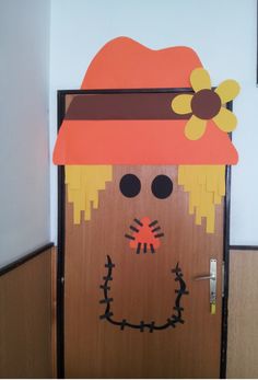 a wooden door decorated with a scarecrow's hat and flower on it,