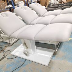 a row of white leather chairs sitting on top of a metal stand in a warehouse