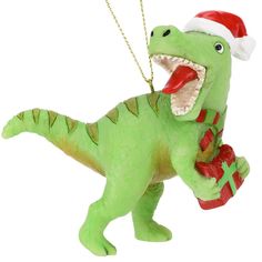 a green dinosaur ornament wearing a santa hat and holding a red present box