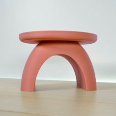 a pink stool sitting on top of a wooden floor