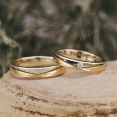 two wedding rings sitting on top of a rock next to each other with a diamond in the middle