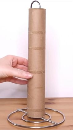 a person is holding a roll of toilet paper in front of a metal object on a table