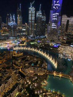 an aerial view of a city at night with lights and water in the foreground