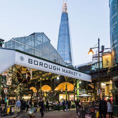 people are walking around an outdoor market with the shardling building in the background