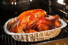 a roasted chicken in an oven with tin foil on the bottom and sides, ready to be cooked