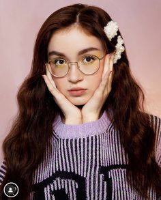 a young woman with glasses and a flower in her hair is posing for the camera