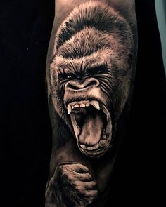 a man's arm with an angry gorilla tattoo on the forearm and hand, in black and white