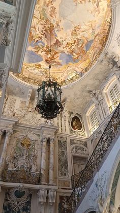 an ornately decorated ceiling and chandelier in a room with white walls, painted ceilings