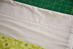 a piece of fabric sitting on top of a cutting board next to a green and white ruler