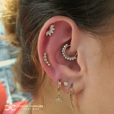 a woman wearing ear piercings with flowers and stars on it's side, in front of her ear