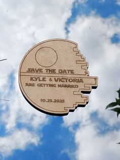 a wooden sign with the words save the date on it in front of a cloudy sky