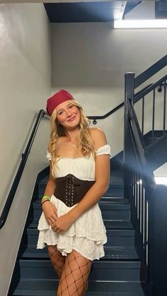 a woman wearing a corset and stockings posing for the camera in front of some stairs