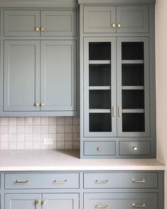 a kitchen with gray cabinets and white counter tops, gold pulls on the cupboards