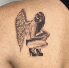 an angel tattoo on the back of a woman's upper arm and shoulder, sitting on a stool