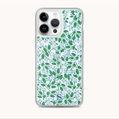 an iphone case with green leaves and blue flowers on the front, against a white background