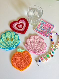 crocheted items displayed on white surface with water glass and bead bracelets