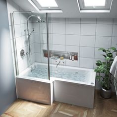 a bathroom with a bathtub, shower head and two plants on the floor next to it