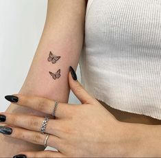 two women with matching butterfly tattoos on their arms, both holding each other's hands