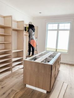 a woman is standing on a ladder in the middle of a room with shelving