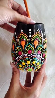 a hand holding a painted wine glass with an orange handle