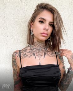 a woman with tattoos on her chest posing for the camera while wearing a black dress