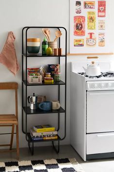 a kitchen area with a stove, microwave and shelf next to a white refrigerator freezer