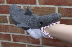 a hand holding a knitted shark head with it's mouth open