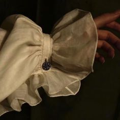 a close up of a person's hand wearing a white blouse