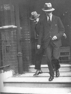 two men in suits and hats are walking down the steps