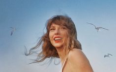 a woman with long hair standing in front of seagulls flying over her head