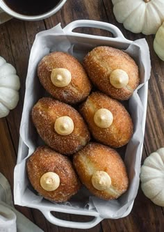 there are many donuts in the basket on the table next to some pumpkins