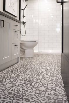 a white toilet sitting in a bathroom next to a walk in shower and tiled floor