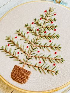 a christmas tree with a potted plant in it on a white tablecloth surrounded by red berries and gold thread