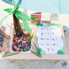 a child is playing with letters and numbers on a table next to a palm tree