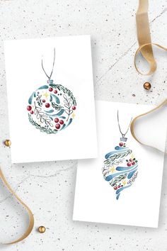 two christmas cards with ornaments on them next to a ribbon and some other items in the background